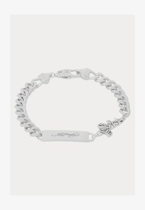 Sidabrinė grandinėlė su stačiakampiu žymekliu, ant kurio graviruotas tekstas, papuošta kryžiumi ir gėlių akcentais. Lygus paviršius, tvirti linkiai.