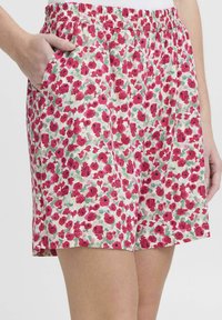 Shorts floreali con vita elastica, caratterizzati da un motivo di fiori rossi e rosa su uno sfondo bianco, e tasche laterali.