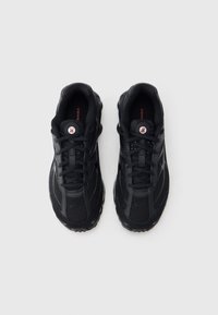 Čierne atletické topánky s hornou časťou z priedušnej sieťoviny, šnurovaním a zaoblenou podrážkou s viditeľnými tlmiacimi prvkami. Detaily tvoria logo.