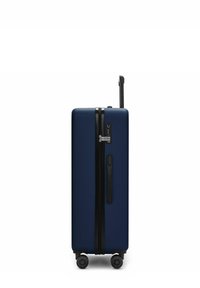 Valigia rigida blu navy in posizione verticale, con quattro ruote, un manico telescopico estensibile, un manico laterale e una serratura combinata integrata.