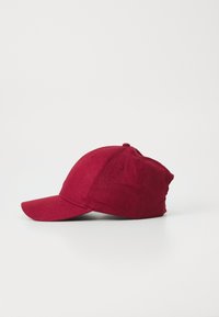 Red baseball cap made of textured fabric with a curved brim, adjustable strap at the back, and a rounded crown.