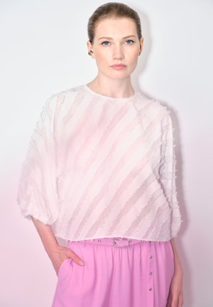 Haut en voile rose clair avec des rayures texturées et des manches larges, associé à un pantalon rose ample avec une boucle en argent et des accents de boutons.
