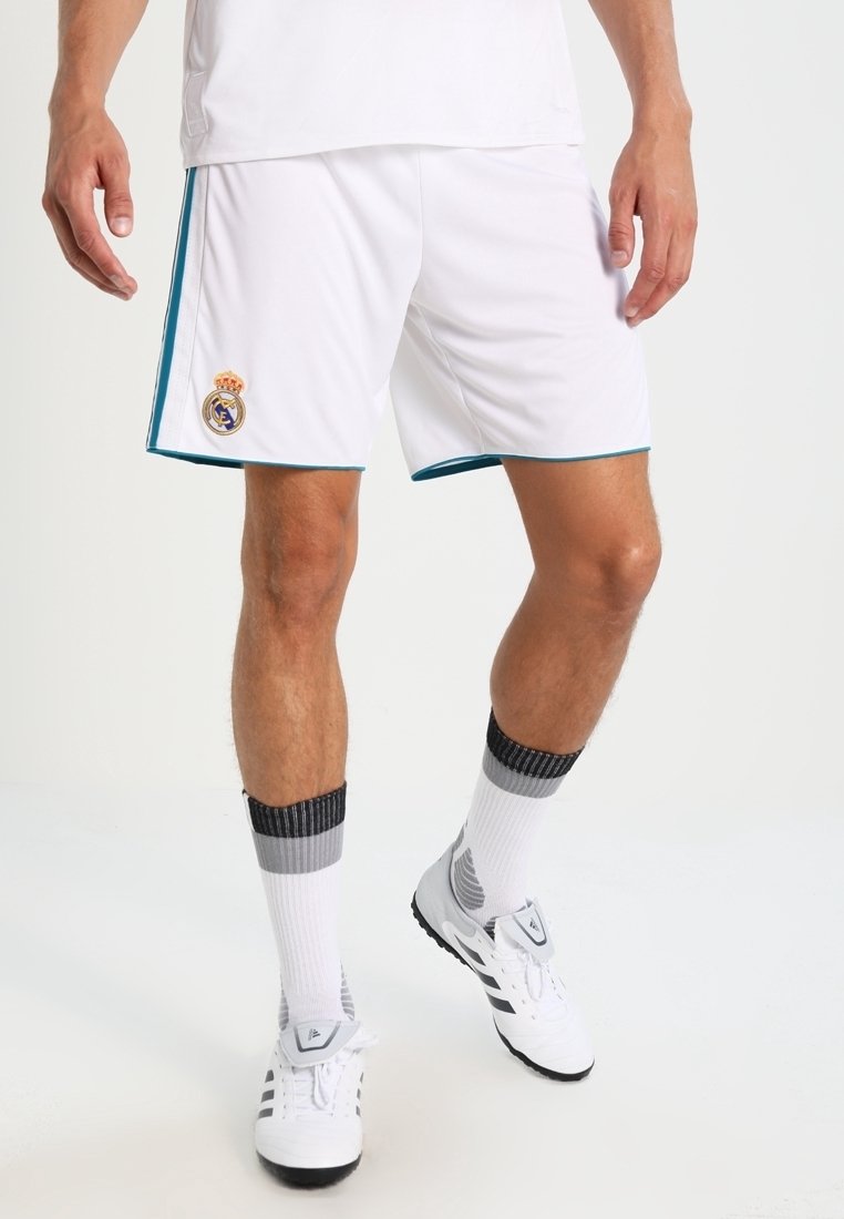 Valkoiset urheilushortsit, joissa on teal-väriset yksityiskohdat ja Real Madridin logo. Yhdistetty harmaaraidallisiin sukkiin ja valkoisiin lenkkarikenkiin. Kevyt ja hengittävä kangas.