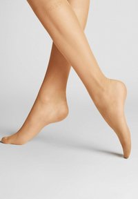 Durchsichtige, hautfarbene Strumpfhosen mit matter Oberfläche und glatter Textur. Sie verfügen über einen markierten Bund und ein eng anliegendes Design, das die Beine bedeckt.