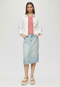 Weiße Jeansjacke über einem rosa gestrickten Top, kombiniert mit einem hellblauen Jeansrock und beigen Plateausandalen. Schlichter, lässiger Look.