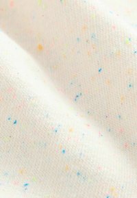 Tessuto di cotone testurizzato in crema, con una varietà di punteggiature multicolori di rosa, giallo e blu, caratterizzato da una finitura liscia e a maglia.