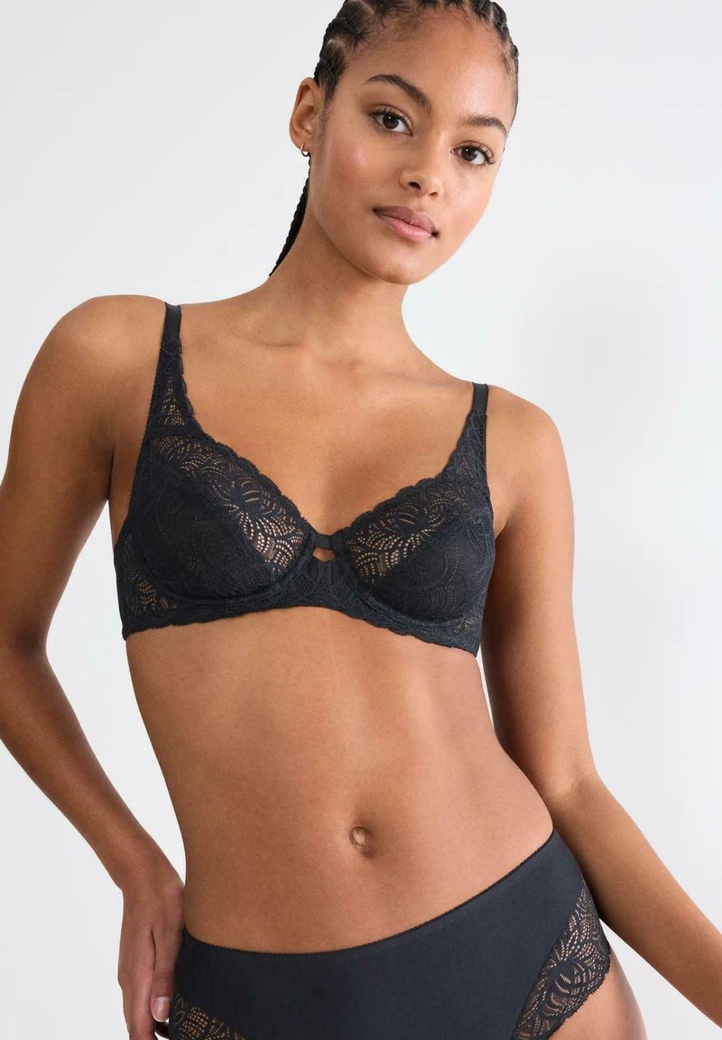 Czarny koronkowy biustonosz w kwiatowy wzór, z regulowanymi ramiączkami i małym wycięciem na przodzie. Miękkie miseczki zapewniają delikatne wsparcie.