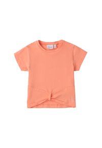 Camiseta de manga corta color coral hecha de algodón suave, con un detalle de nudo en el frontal y un pequeño logo decorativo en la esquina inferior.