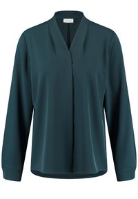 Blusa lunga color teal con scollo a V e vestibilità rilassata. Realizzata in un tessuto leggero e morbido con sottili pieghe sul davanti.