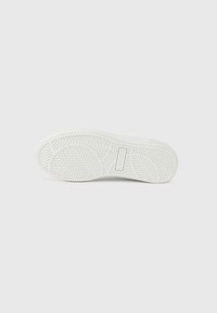 Λευκή σόλα αθλητικού παπουτσιού με υφή σε σχήμα ψαροκόκκαλου. Διαθέτει ανάγλυφο λογότυπο και λείο φινίρισμα. Μινιμαλιστικός σχεδιασμός χωρίς ορατή φθορά.