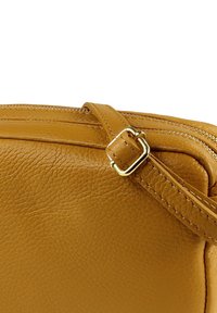 Cognackleurige leren schoudertas met een gestructureerde afwerking, een ritssluiting en een accenten van een gouden gesp aan het verstelbare hengsel.