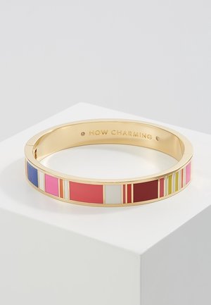 Bracelet rigide ton or avec émail rectangulaire coloré en bleu, rose, rouge, blanc, bordeaux, bandes jaunes, et « HOW CHARMING » gravé à l'intérieur.