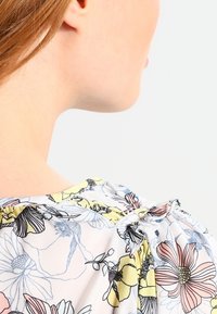 Bloes met bloemenmotief, gemaakt van een lichtgewicht, doorschijnende stof met een pastelkleurenpalet, met een gerimpelde halslijn en een strikdetail op de rug.