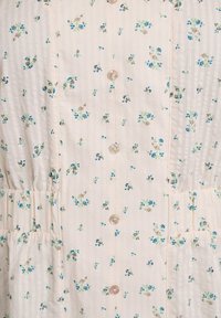 Vestido floral blanco con pequeños patrones azules y verdes. Presenta rayas verticales, botones tipo perla y un detalle de cintura fruncida.