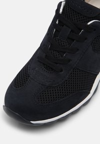 Zwarte sneaker met mesh-panelen en suède accenten. Bevat ronde veters, een gepolsterde kraag en witte buitenzooldetails.