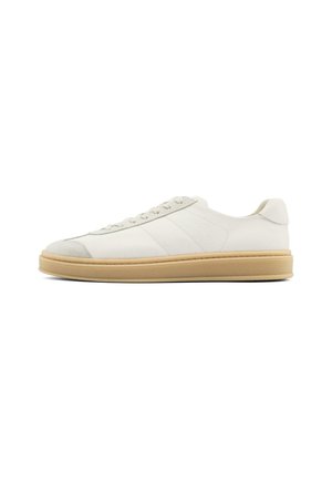Baskets en suède blanches avec une texture lisse, bout arrondi, laçage à l'avant et semelle en caoutchouc beige. Présentent de subtiles rayures latérales et des accents sur le talon.