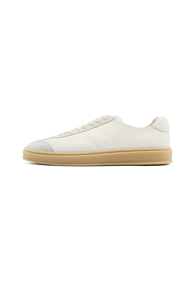 Weiße Wildledersneaker mit glatter Oberfläche, runder Zehenpartie, Schnürung und einer tanfarbenen Gummisohle. Mit dezenten Streifen an den Seiten und Akzenten an der Ferse.