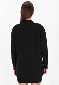 Schwarzer übergroßer Pullover mit hohem Kragen, gerippten Bündchen und Saum. Aus weichem Material gefertigt, mit einer entspannten Passform und seitlichen Schlitzen.