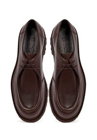 Scarpe in pelle marrone con punta rotonda, superficie liscia, cuciture discrete e suola in gomma testurizzata con piccoli motivi in rilievo.