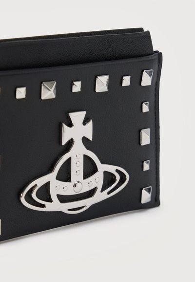 Μαύρο δερμάτινο πορτοφόλι με ασημένιες πυραμιδοειδείς τρούκ και μεγάλο γυαλιστερό ασημένιο εμβληματικό σφαιρίδιο με σταυρό στην πρόσοψή του.