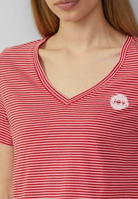 Rot-weißer gestreifter T-Shirt mit V-Ausschnitt. Verfügt über ein kleines "JOY"-Logo in einem kreisförmigen Akzent auf der Brust. Weicher Stoff.