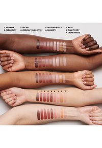 Neun Arme zeigen verschiedene Lippenstiftproben in Nuancen von tiefem Burgunder bis zu sanften Nudetönen, angeordnet von dunkel nach hell auf einem neutralen Hintergrund.