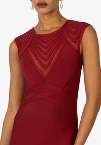 Rotes Kleid mit strukturiertem, geschichtetem Mesh-Oberteil mit geometrischen Falten und taillierter Silhouette. Kurzärmel und glatter Stoffabschluss.
