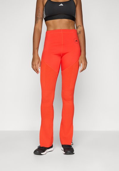 Røde atletiske leggings med ribbet tekstur, høj taljedesign, sidepaneldetaljer og logo på låret, parret med sorte sko.