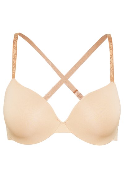 Beige padded bra with a smooth texture, featuring crisscross straps and a branded metallic strap along the back.