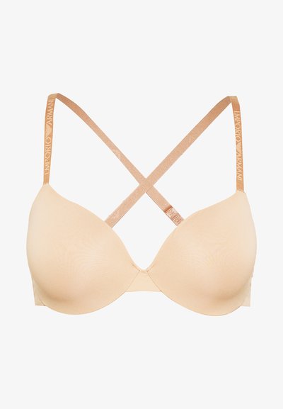 Beige vyztužená podprsenka s hladkým povrchem, s křížovými ramínky a kovovým branded páskem na zadní straně.