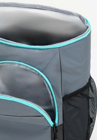 Sac à dos gris avec un sommet arrondi, présentant des accents turquoise, plusieurs poches zippées et une poche latérale en mesh pour un stockage supplémentaire.