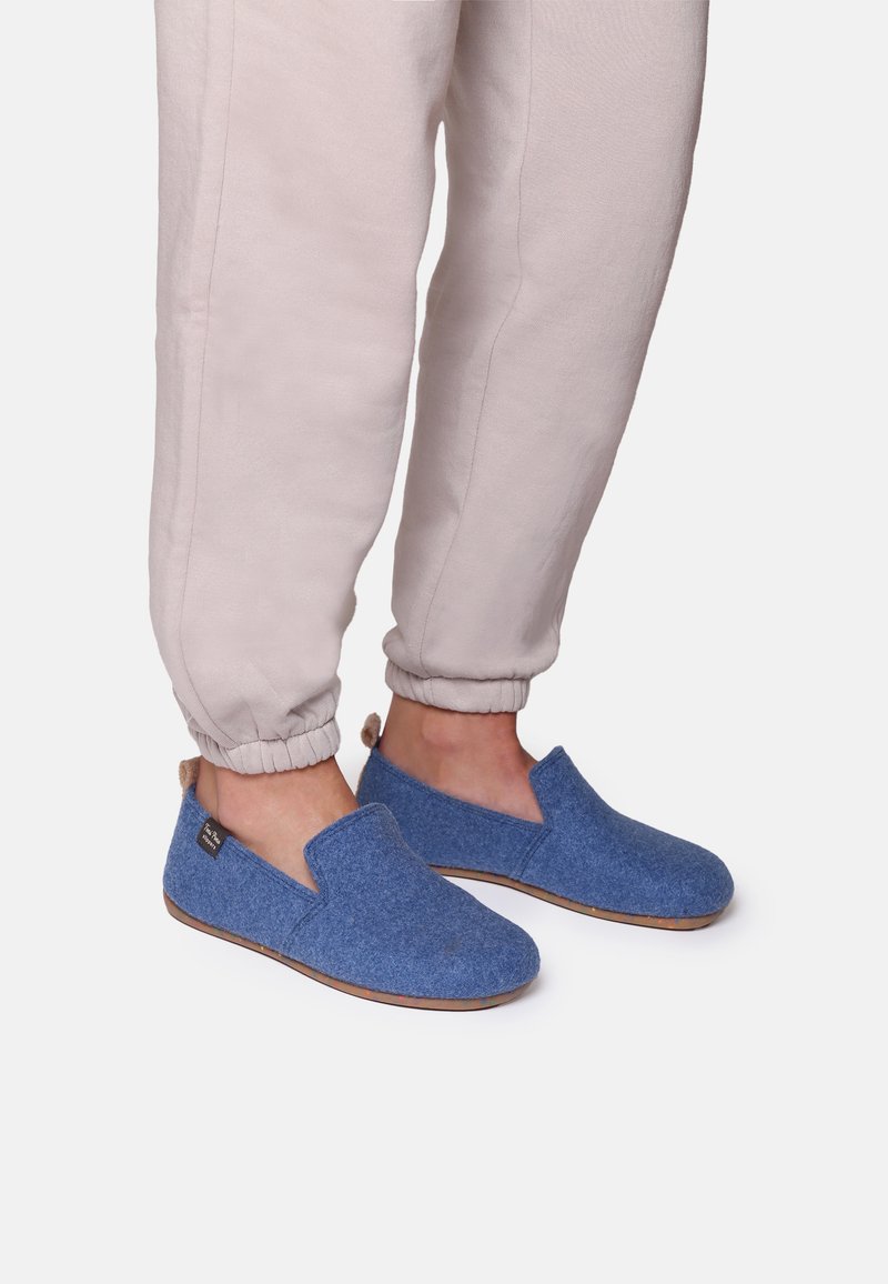 Blue felt slip-on shoes with a textured surface and rubber soles, paired with light beige cuffed pants.