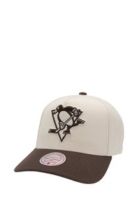 Gorra de color crema con visera marrón oscuro. Presenta un logo bordado de un pingüino y palos de hockey cruzados en el frontal. Con correa ajustable en la parte posterior.