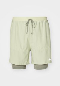 Pantalones cortos de running verde claro con cinturilla elástica, cordón gris, capa de compresión interna y logo blanco de Nike en el dobladillo.