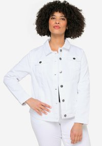 Chaqueta de mezclilla blanca con cierre de botones en el frente, dos bolsillos en el pecho y mangas largas. Presenta botones en tono plateado y un diseño de cuello clásico.