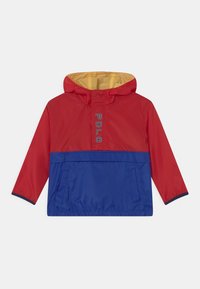 Červená a modrá větrovka se žlutou kapucí, s přední kapsou a logem „POLO“. Hladký povrch a elastické manžety.