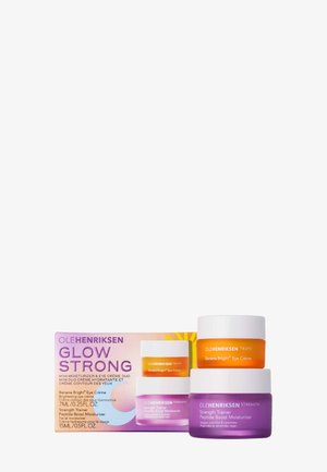 Due barattoli per la cura della pelle Ole Henriksen, uno arancione etichettato Banana Bright Eye Crème e uno viola etichettato Strength Trainer Peptide Boost Moisturizer, con scatola del prodotto.