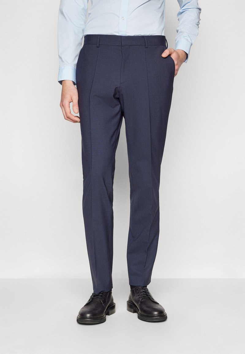 Mörkblå skräddarsydda byxor med en mjuk textur, slim fit, två sidofickor och en veck framtill, i kombination med svarta kostymskor.