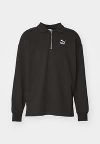 Zwarte poloshirt met lange mouwen van katoen, met een col met halve rits. Voorzien van een wit Puma-logo aan de linkerkant, geribde manchetten en een relaxte pasvorm.