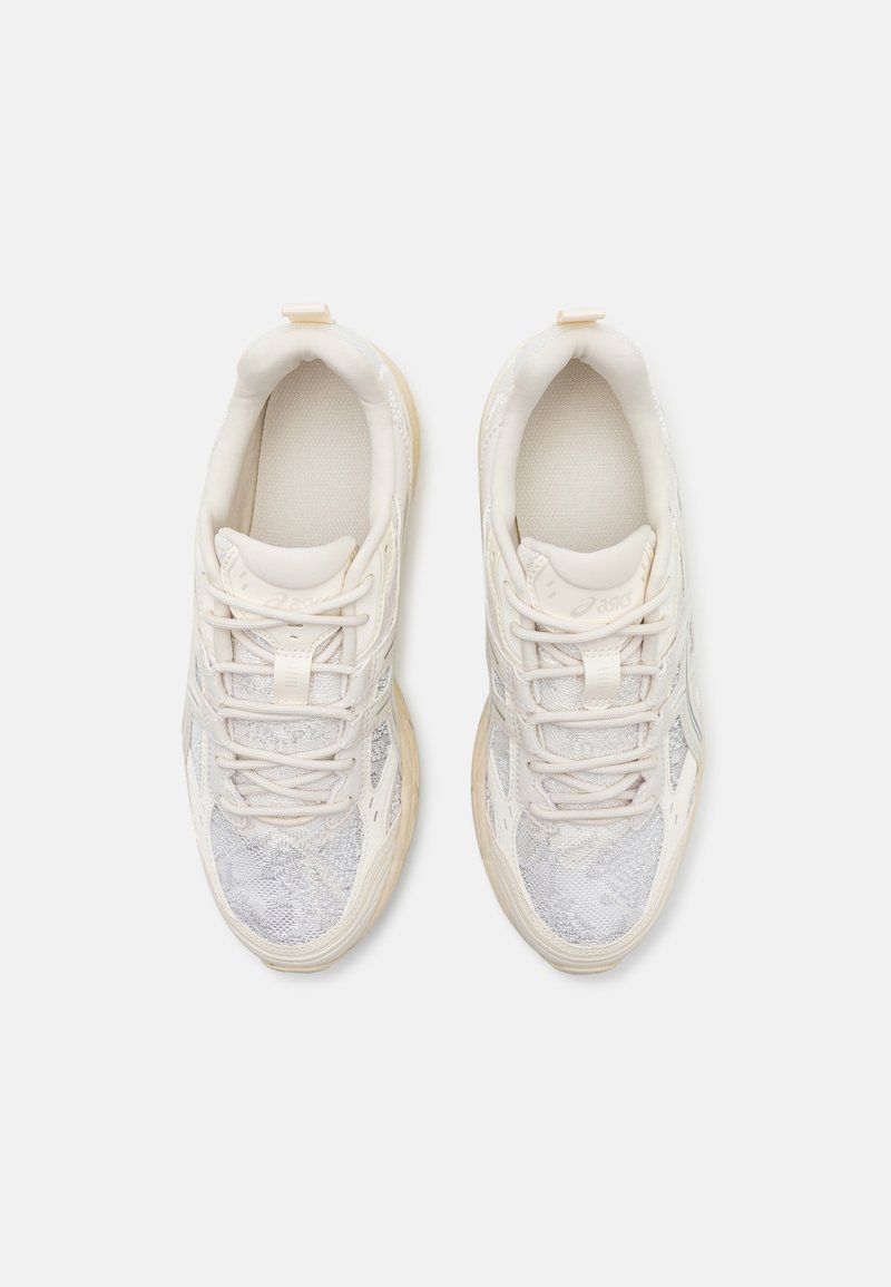 Weiße Mesh-Sneaker mit einem strukturierten Design, leichtem Material und cremefarbenen Akzenten. Mit Schnürsenkeln und einem gepolsterten Innenbereich für Komfort.
