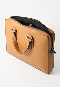 Borsa da lavoro in pelle tan con chiusura a zip, fodera interna nera, due manici robusti e dettagli in hardware color argento.