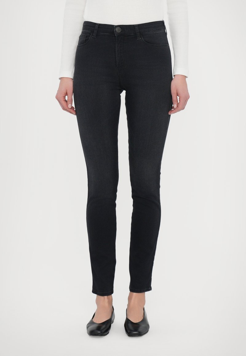 Svarta smala jeans med en slät denimtextur och design för fem fickor. Har en knappstängning framtill och diskreta bältesöglor.