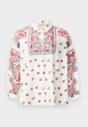 Blouse blanche avec des motifs paisley rouges et marins, fermeture à boutons sur le devant et manches longues. Tissu léger avec des détails complexes.