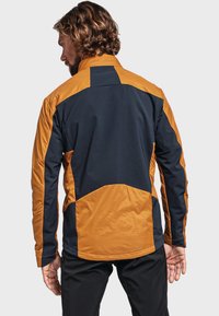 Veste pour homme avec un mélange de panneaux bleu marine et orange, un col montant, des poches zippées et un tissu texturé et isolant.