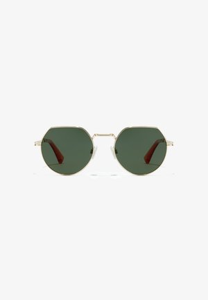 Octagonal sunglasses with green lenses, thin gold metal frame, and transparent nose pads. Arms have a subtle brown accent.