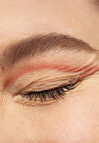 Close-up of a closed eyelid featuring light skin texture, dark eyelashes, and a thin, reddish line across the eyelid crease.