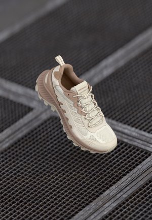 Light beige athletic shoe with a mesh upper, molded accents, reinforced toe cap, and textured rubber sole. Features a pull tab for easy wear.