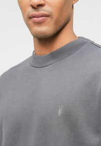 Γκρι φούτερ με υφή, διαθέτει στρογγυλή λαιμόκοψη και ριμπ ύφαλες. Σημαντικό μικρό κεντημένο λογότυπο στο στήθος.