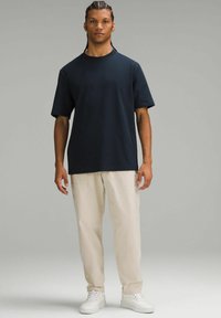 Tricou din bumbac navy cu mâneci scurte, asortat cu pantaloni bej deschis, completat cu adidași albi. Design simplu, cu o croială relaxată.
