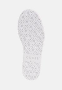 Soletta di scarpa bianca con superficie decorata che presenta il logo "GUESS" in rilievo al centro e un bordo liscio e arrotondato.